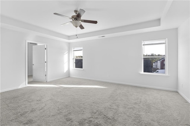 unfurnished room featuring a raised ceiling, ceiling fan, and light carpet