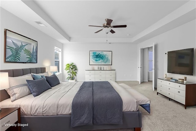 carpeted bedroom with ceiling fan and a tray ceiling