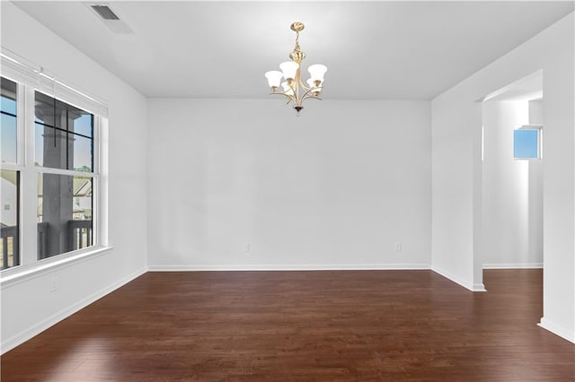 spare room with a notable chandelier and dark hardwood / wood-style floors