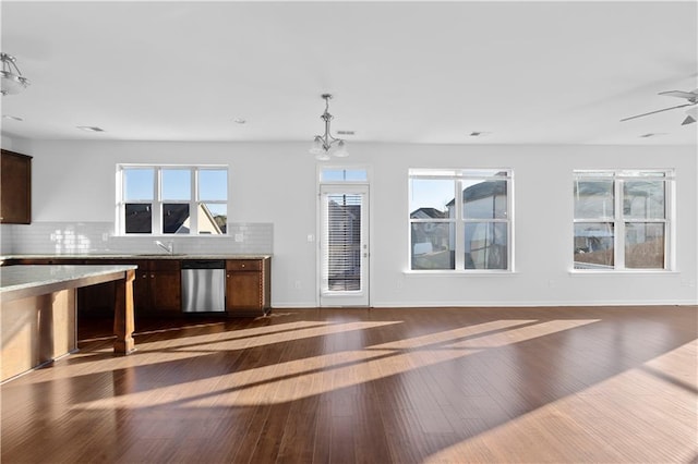 kitchen with dishwasher, dark hardwood / wood-style floors, sink, decorative light fixtures, and backsplash