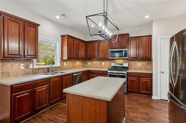 kitchen featuring appliances with stainless steel finishes, sink, dark hardwood / wood-style flooring, hanging light fixtures, and a center island