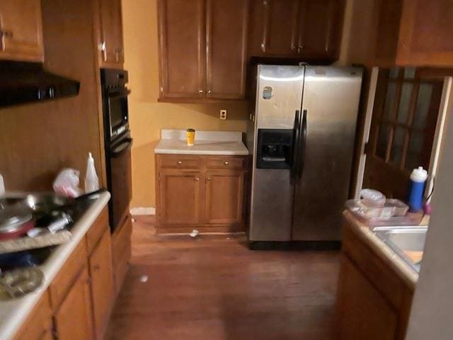 kitchen with stainless steel refrigerator with ice dispenser, dark wood-type flooring, and oven