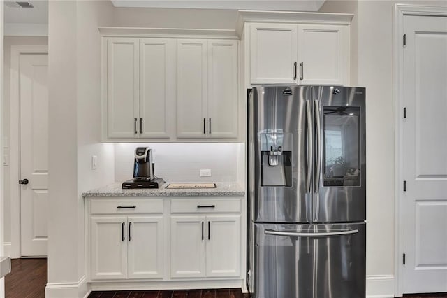 kitchen featuring stainless steel refrigerator with ice dispenser, decorative backsplash, white cabinets, dark wood finished floors, and light stone counters