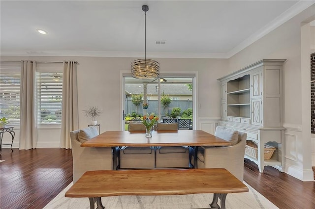 dining area with crown molding, dark wood-type flooring, a chandelier, recessed lighting, and a wainscoted wall