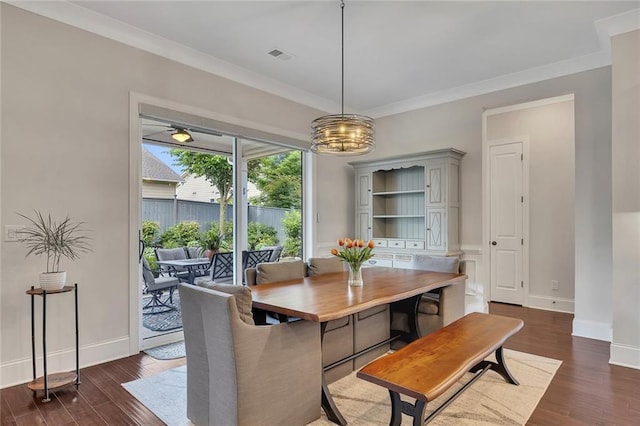 dining space featuring dark wood-style floors, baseboards, a chandelier, and crown molding