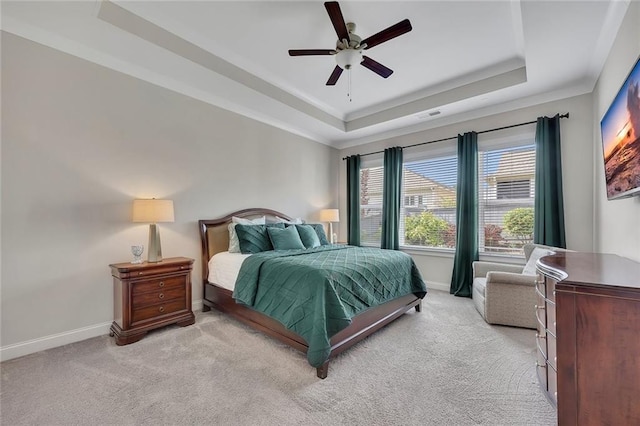 bedroom with a raised ceiling, baseboards, and light colored carpet