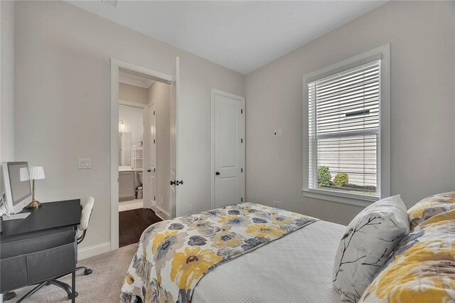 bedroom with carpet floors, an office area, baseboards, and connected bathroom