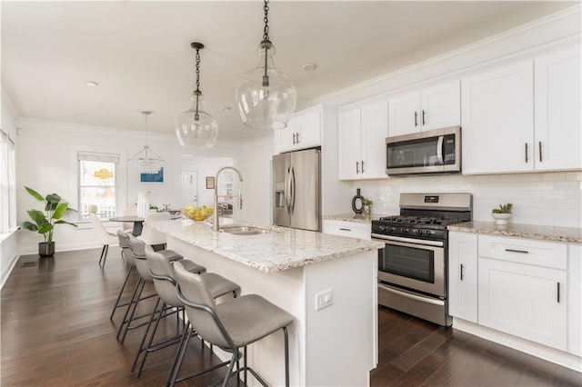 kitchen with stainless steel appliances, tasteful backsplash, ornamental molding, and white cabinets