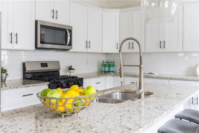 kitchen featuring tasteful backsplash, a breakfast bar area, appliances with stainless steel finishes, white cabinets, and a sink