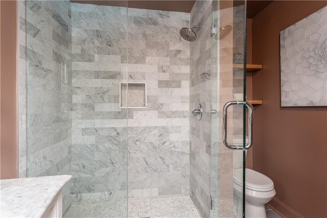 bathroom with baseboards, vanity, toilet, and a shower stall