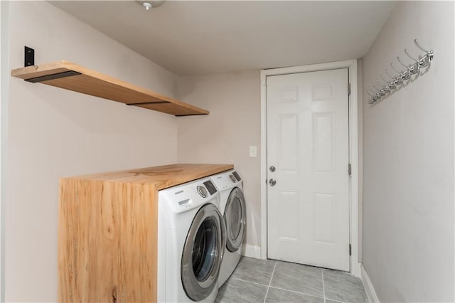 laundry room featuring laundry area, light tile patterned floors, washing machine and dryer, and baseboards