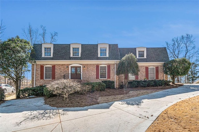 view of property featuring roof with shingles and brick siding