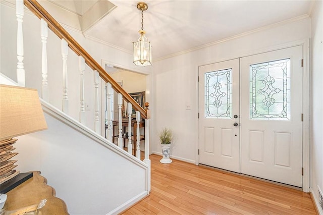 entryway featuring wood-type flooring, crown molding, and stairs