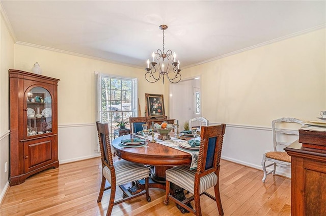 dining room featuring baseboards, light wood-style flooring, a chandelier, and crown molding