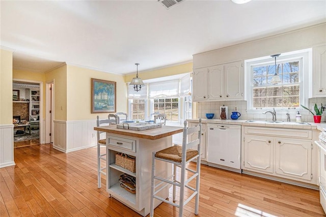 kitchen featuring dishwasher, a breakfast bar, light wood finished floors, and white cabinetry