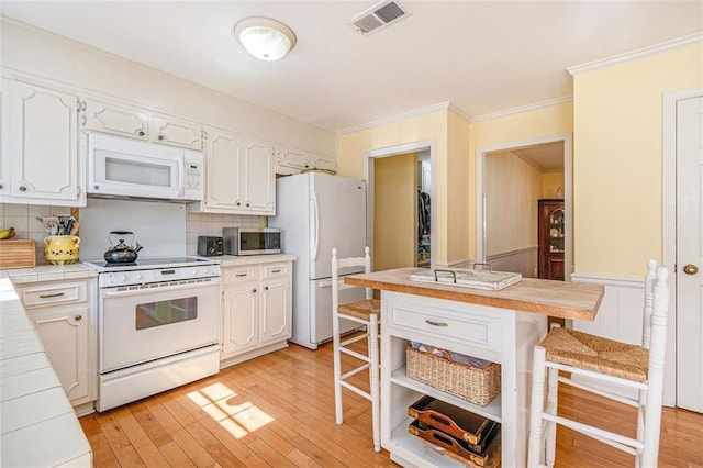 kitchen featuring tile counters, white appliances, visible vents, and a breakfast bar area