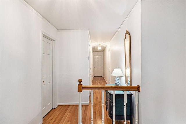 corridor with light wood-style flooring, baseboards, and crown molding