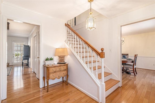 stairway with hardwood / wood-style flooring, a chandelier, and crown molding