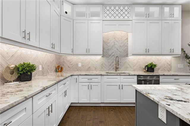 kitchen featuring light stone counters, stainless steel dishwasher, decorative backsplash, white cabinetry, and sink