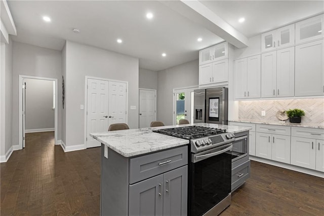 kitchen with stainless steel appliances, white cabinets, light stone counters, tasteful backsplash, and a kitchen island