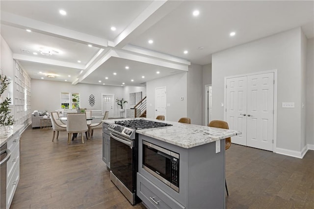 kitchen featuring dark wood-type flooring, stainless steel appliances, a kitchen island, gray cabinets, and a kitchen breakfast bar