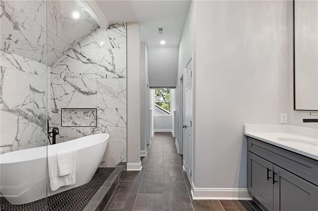 bathroom featuring tile walls, a bathing tub, and vanity