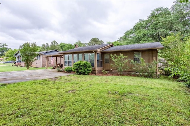 single story home with a chimney, driveway, a front lawn, and board and batten siding