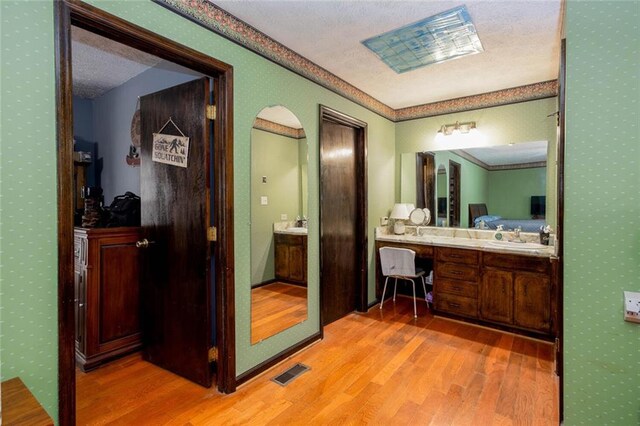 bathroom featuring wood finished floors, vanity, and wallpapered walls