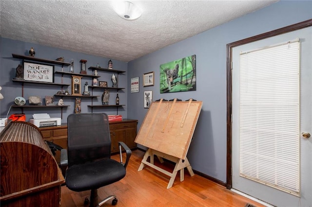 home office featuring wood finished floors, a textured ceiling, and baseboards