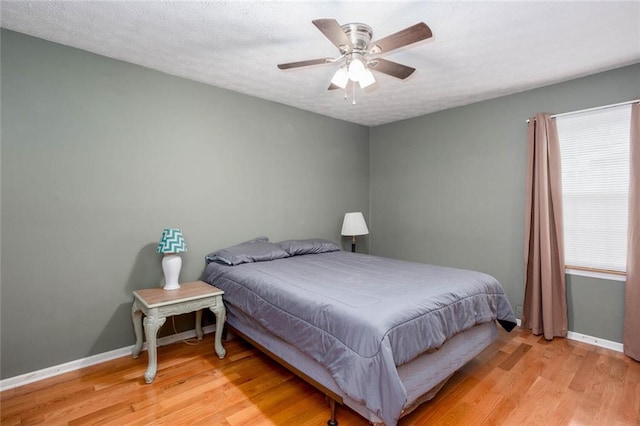 bedroom featuring baseboards, wood finished floors, and ceiling fan