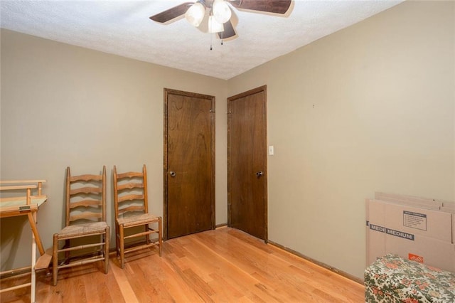 living area featuring a ceiling fan, wood finished floors, and a textured ceiling