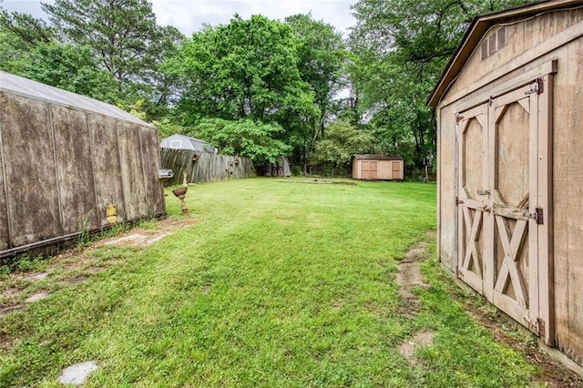 view of yard featuring a shed, an outdoor structure, and view of wooded area