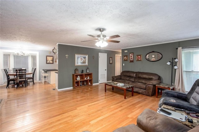 living area with a chandelier, a textured ceiling, light wood-type flooring, ceiling fan, and ornamental molding