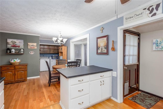 kitchen featuring washer and clothes dryer, ornamental molding, dark countertops, a chandelier, and light wood finished floors