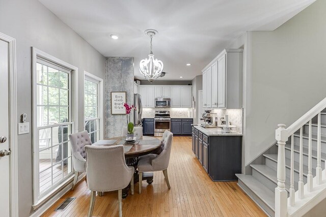 1045 Legacy Walk, Woodstock, GA 30189 - dining room with a chandelier, light wood-style flooring, stairs, and recessed lighting