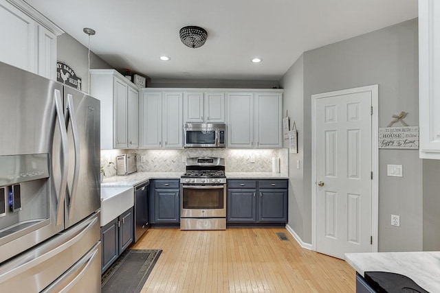 1045 Legacy Walk, Woodstock, GA 30189 - kitchen with appliances with stainless steel finishes, backsplash, light wood-style flooring, white cabinets, and recessed lighting
