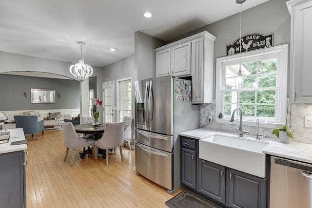 1045 Legacy Walk, Woodstock, GA 30189 - kitchen with stainless steel appliances, a chandelier, a sink, open floor plan, and tasteful backsplash