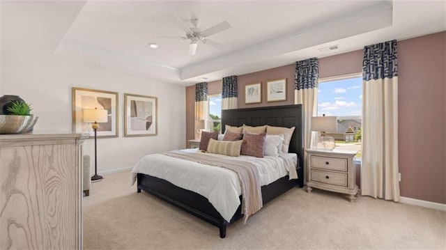 carpeted bedroom with a tray ceiling and ceiling fan