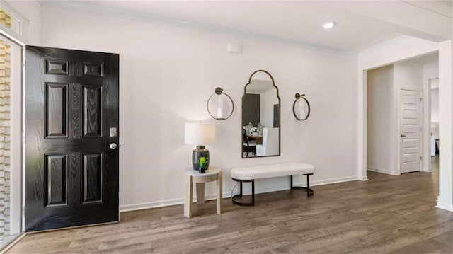 foyer entrance with ornamental molding and wood-type flooring