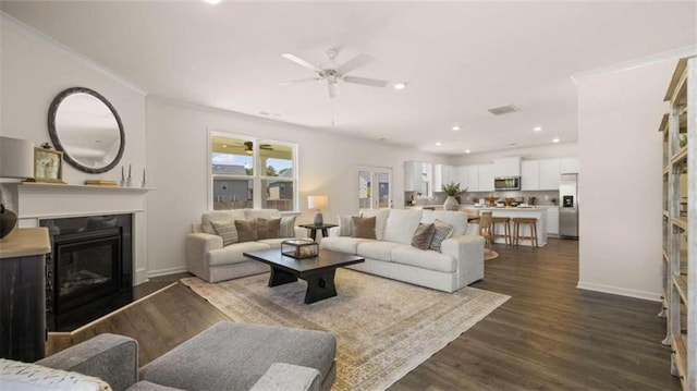 living room featuring ornamental molding, ceiling fan, and dark hardwood / wood-style floors