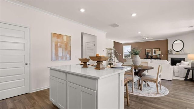 kitchen with ceiling fan, a center island, dark hardwood / wood-style flooring, and crown molding