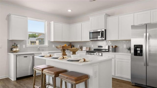 kitchen featuring dark wood-type flooring, appliances with stainless steel finishes, a kitchen island, and white cabinetry