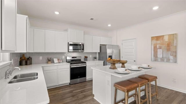 kitchen with tasteful backsplash, stainless steel appliances, a kitchen breakfast bar, a center island, and sink