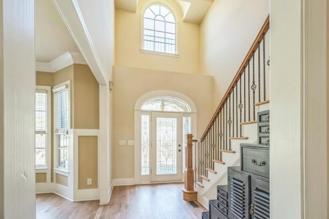 entryway featuring light wood-type flooring, a healthy amount of sunlight, and ornamental molding