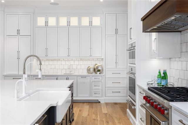 kitchen featuring white cabinets, custom exhaust hood, sink, and stainless steel stove