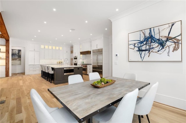 dining space with crown molding and light hardwood / wood-style flooring