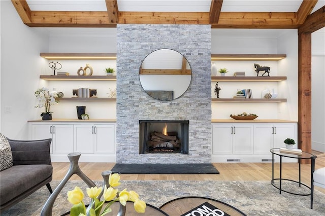 living room with a fireplace, light wood-type flooring, and beamed ceiling