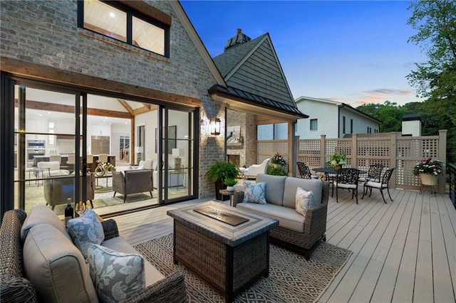 deck at dusk featuring an outdoor living space with a fire pit