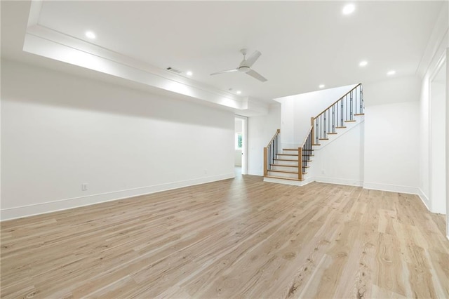 unfurnished living room with ceiling fan, light wood-type flooring, and a tray ceiling