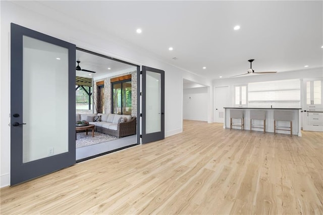 unfurnished living room with ceiling fan, french doors, and light hardwood / wood-style flooring